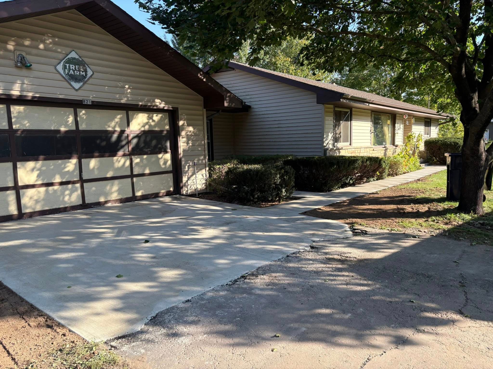 Single-story home with garage and driveway, surrounded by landscaping and trees.