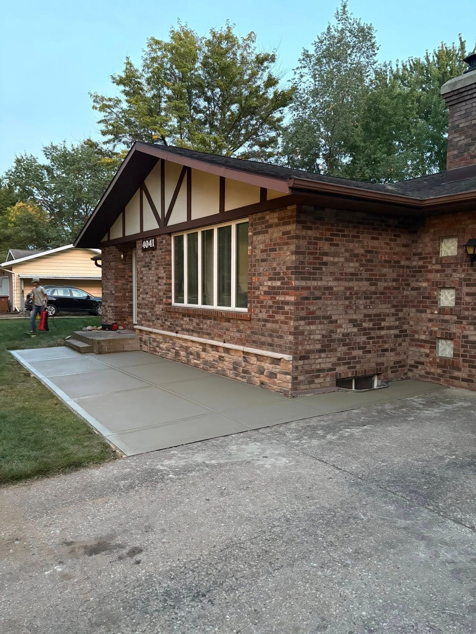 Exterior view of a brick house with a new concrete patio and landscaping.